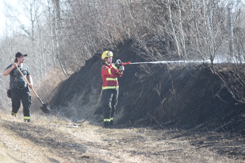 Two Barrhead Regional Fire Services firefighters work on the border of a wildfire Township Road 563A near Range Road 13.