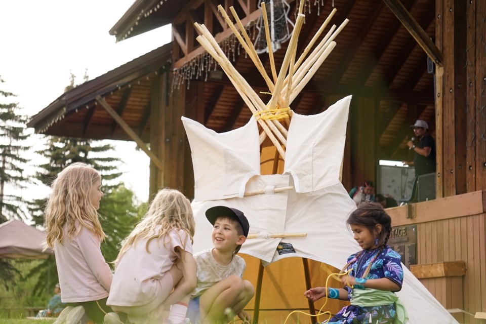 Twins Lindsey and Emily Marchese-King, Jack Jackson, and Dawn Jacobs play together in the tipi in front of the stage.                                