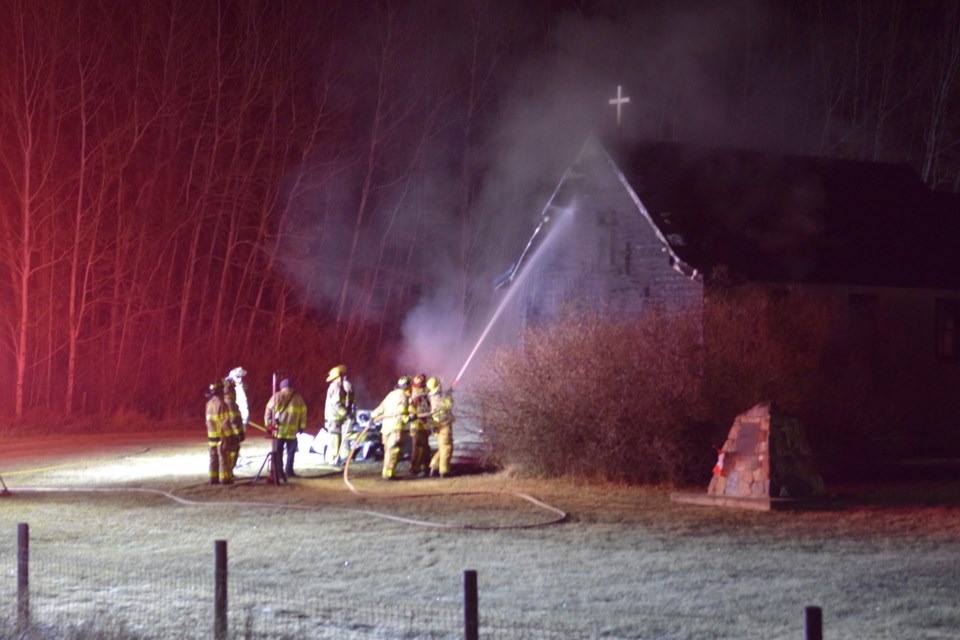 Barrhead Regional Fire Services firefighters spray water on fire from the roof of St. Aidan's Church.