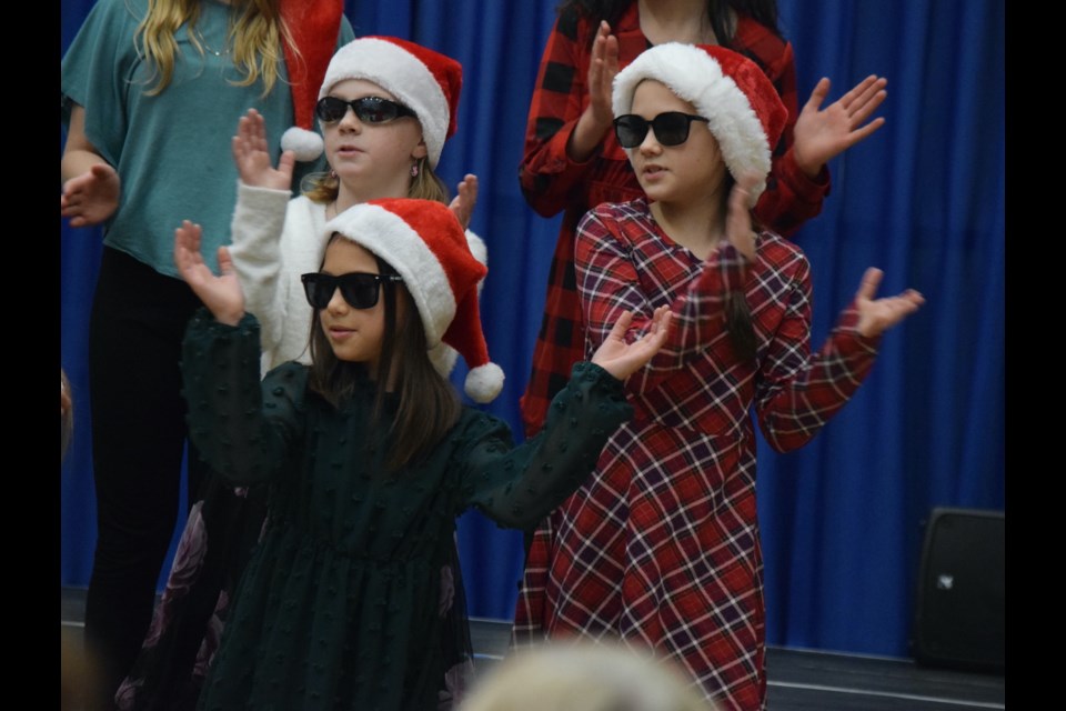 Freya Grove (bottom front), Evelynn Bartholow (top left), and Aven Barton (top right) perform "La Danse du Père Noël" as part of the Grade 4-5 F choir. Teacher Joanne Kolstad explained that the song, "La Danse du Père Noël," is about Santa dancing and celebrating after all of his hard work of delivering presents is done.