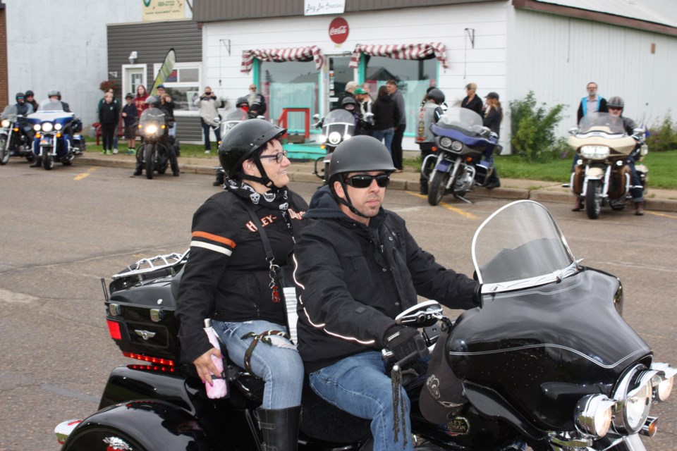 Friends, neighbours, well-wishers and motorcycle enthusiasts from all over came together in front of the Whistlestop Cafe in Boyle July 18 in memory of former owner George Lakatos, who passed away suddenly after he and wife Sharon decided to close the popular restaurant earlier this year. Pictured, following a few words to the assembled crowd from Sharon, she hopped on the back of George’s Harley Davidson, driven by best friend Chris McQuinn and led a leather-clad group of bikers down the highway to Ashmont, all in memory of their fallen husband, father and friend.
Chris Zwick/T&C