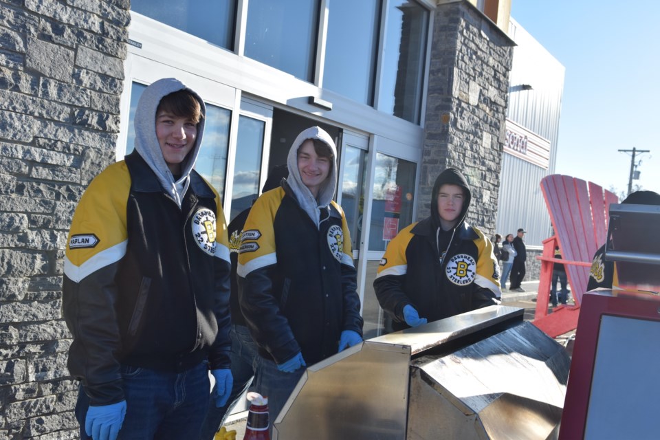 Barrhead Steelers Magnus Kaplan, Carson Anderson, and Nathan Batty man the grill, cooking hot dogs for those who donated to FCSS' Christmas hamper.

