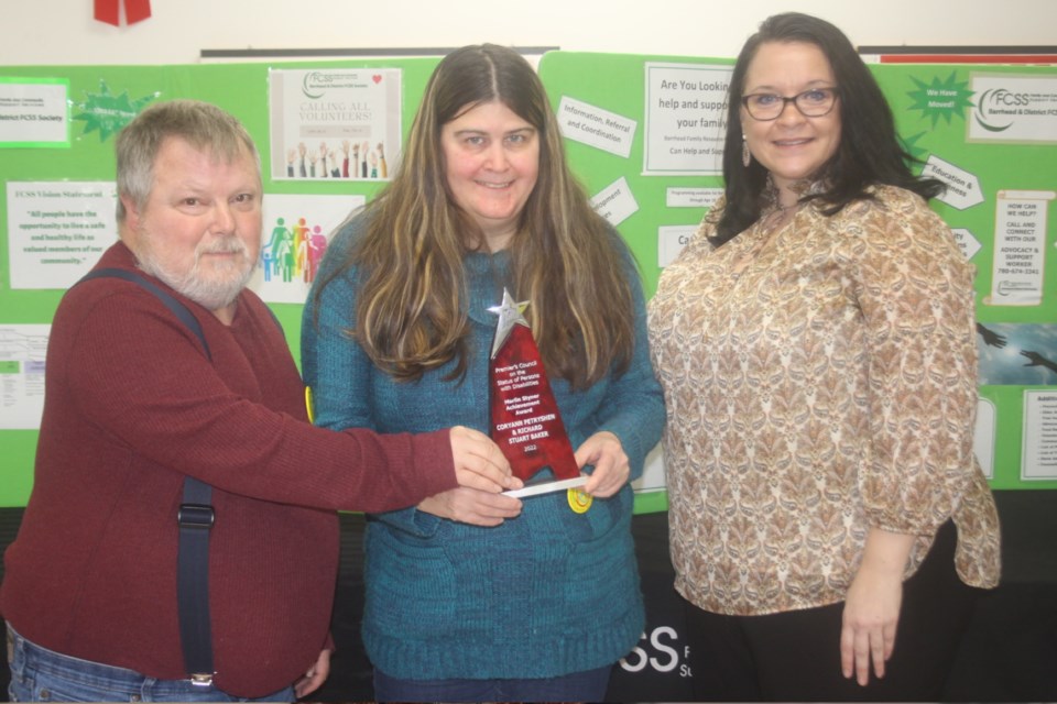 Stuart Baker and CoryAnn Petryshen stand with Katie Suvanto, who presented the couple with the Marlin Styner Achievement Award on behalf of the Premier’s Council on the Status of Persons with Disabilities during the “We Care” pancake breakfast at the Barrhead Senior’s Drop-in Centre on Dec. 3. The award is normally presented to an individual who has not allowed their disability to become a barrier in pursuing personal and professional excellence, but Stuart and CoryAnn were jointly nominated for the award for their work at the Ripple Connection. 