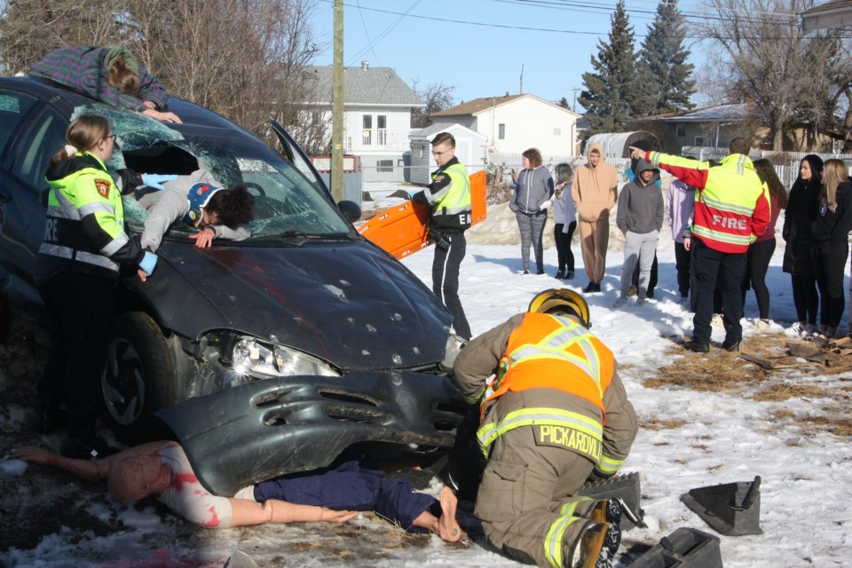 While St. Mary students look in the background, firefighters and emergency medical services work to extricate the injured passengers of the mock accident. 