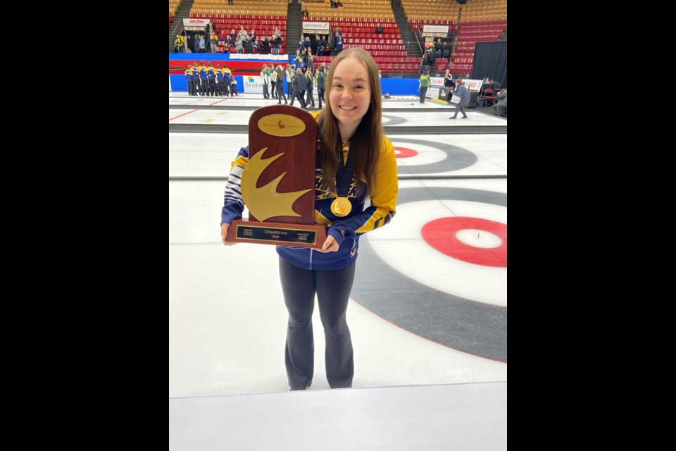Barrhead curler Payton Sonnenberg holding the Canadian Collegiate Athletic Association (CCAA) Women's Curling Championship trophy. 