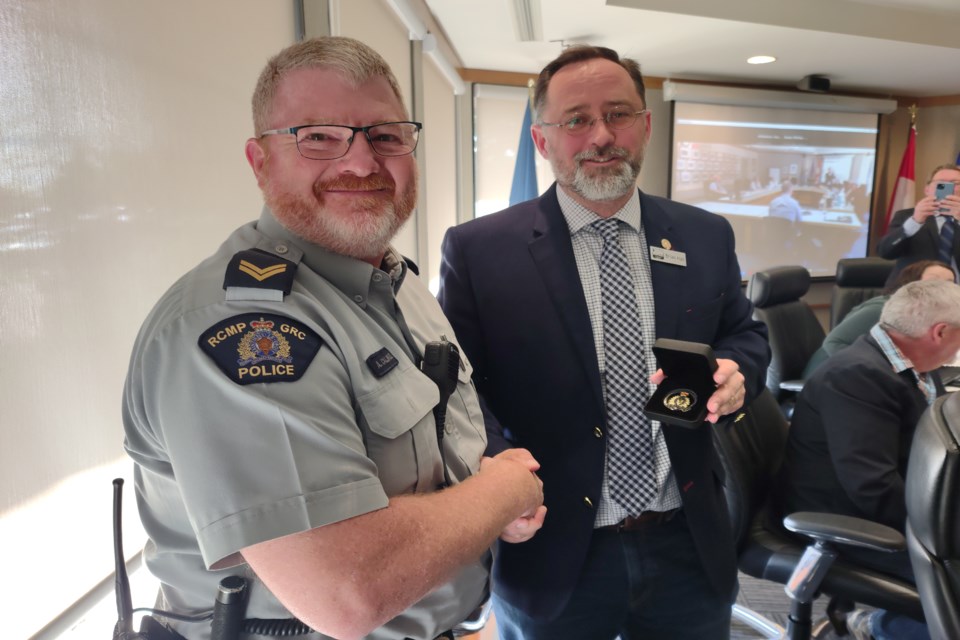 Athabasca RCMP Cpl. Alan Caldwell hands over a challenge coin to Athabasca County reeve Brian Hall during the county’s May 26 meeting where he and Boyle Cpl. Gavin Bergey filled council in on various issues involving police work in the region.