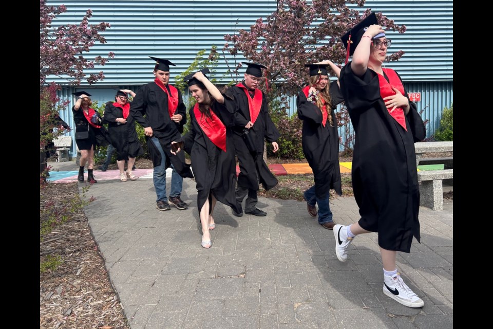 While on their way to the convocation ceremony, the R.F. Staples graduates must hold their caps to keep them from flying away in the high wind on May 31.