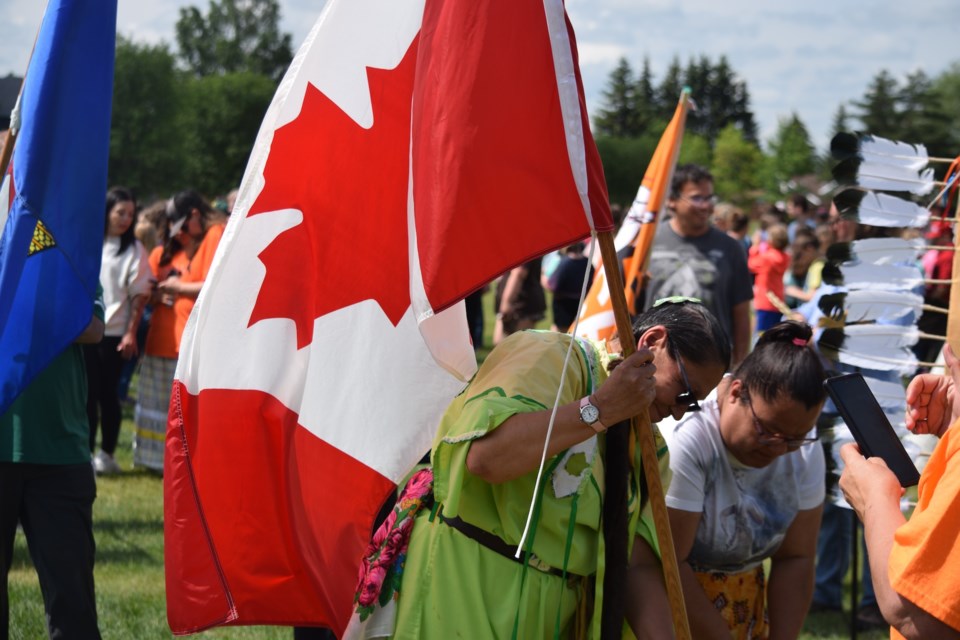 Robin Berard putting the Canadian flag into its stand following the National Indigenous Day walk at Cecile Martin Park.