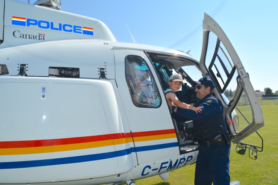 Dozens of Westlock and area residents helped celebrate the Westlock Community Victim Services Unit’s (WCVSU) 30th anniversary, in partnership with Westlock RCMP, with a summer celebration Aug. 26, at the Westlock RCMP Detachment. The event featured several RCMP units including the RCMP race car, RCMP Air Services and RCMP Police Dog Services, along with a barbecue presented by VSU volunteers and several activities for families including a caricature artist and dunk a cop. Pictured, Special Const. Al Miller with the RCMP Air Services Unit helps Jasper McArthur of Westlock out of the helicopter that was part of the RCMP Air Services display Aug. 26 at the Westlock VSU Summer Celebration, which was held to celebrate 30 years of the victim services unit in the community.