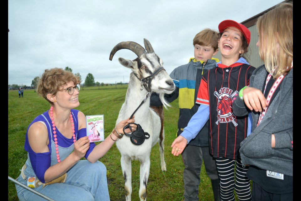 Juliet Sehn, right, laughs as she feeds Ivan the goat with Unforgoatable Treats, as handler Chelsey Wiesinger looks on during the Clyde Summer Solstice June 18.