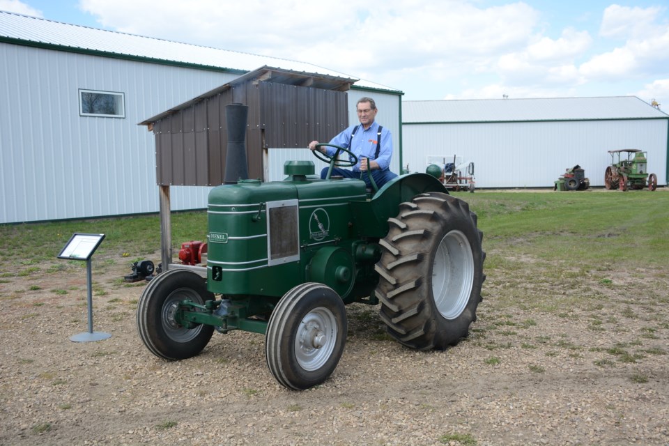 After demonstrating the unique shotgun-shell-style start up of his restored one-cylinder Field Marshall tractor, Elmer Guelly drives it away to put it back under cover at the opening of the Canadian Tractor Museum. 