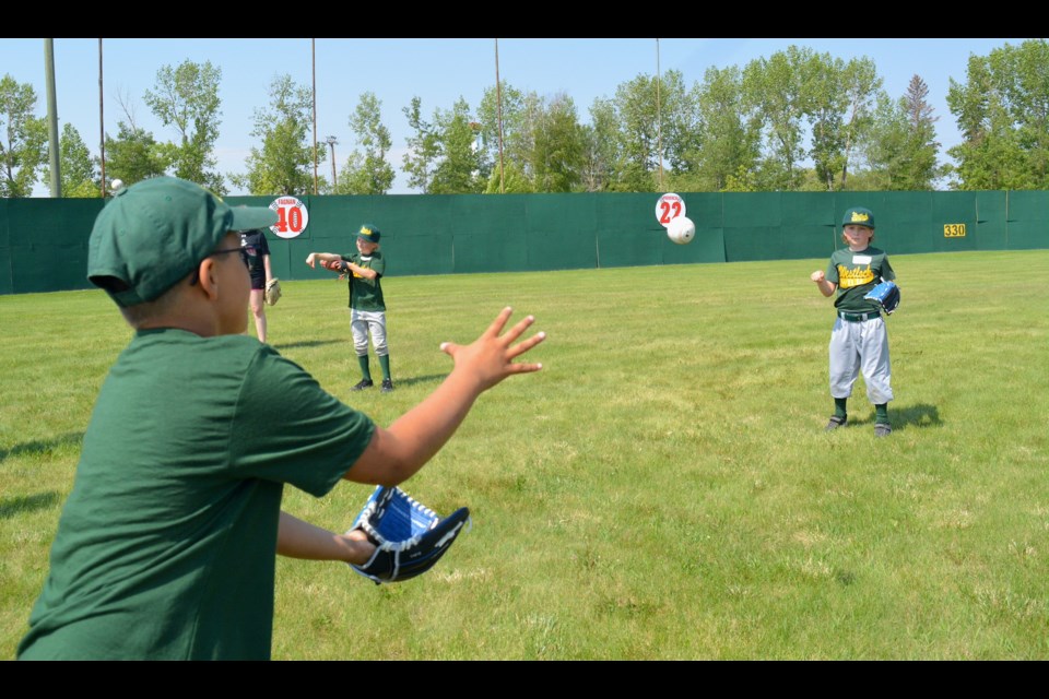 Around 110 young ball players ages four to 13 participated in the Westlock Red Lions’ second-annual, all-day clinic hosted in conjunction with Westlock Minor Ball May 27 at Keller Field. Pictured is Kade Barrit tossing a ball to Carter Brown at the throwing station.