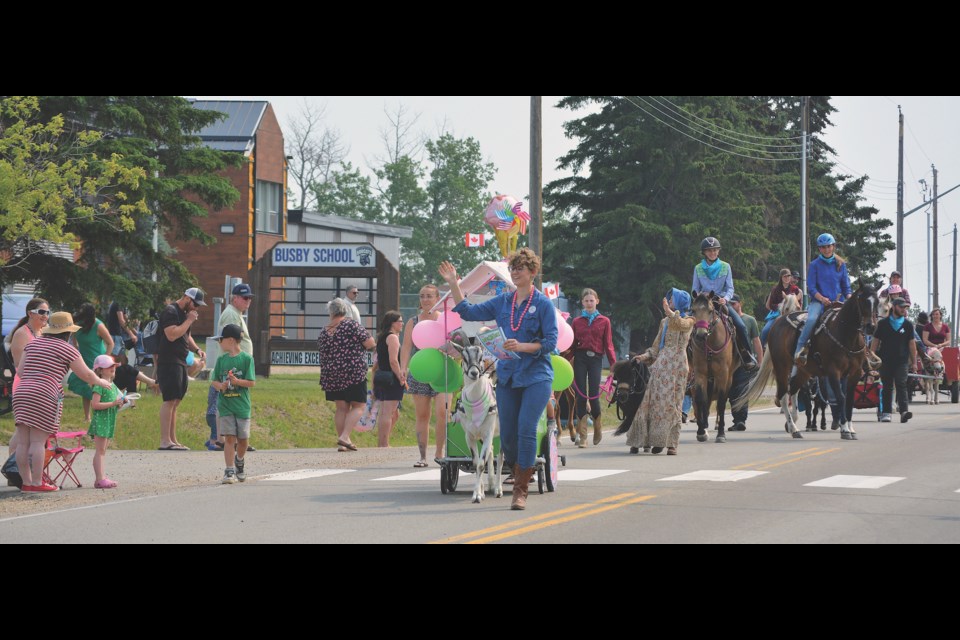Chelsey Wiesinger waves to the crowd as she and Ivan the goat lead the June10 parade down main street in Busby.