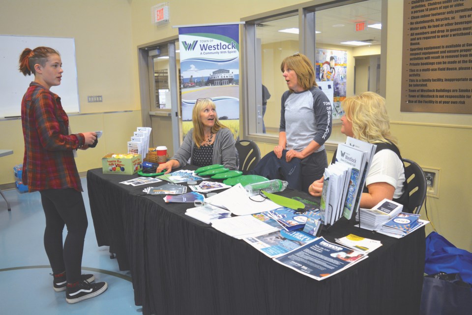 R.F. Staples School Grade 11 student Katie Midgett, left, speaks with the Town of Westlock lifeguard and swim instructor Grace Feheley about job opportunities as a lifeguard with the town this summer, while town employee Vivian Zittlaw, left, and FCSS program coordinator Maureen Schiller look on during the Westlock and District Chamber of Commerce trade show and career fair April 26 at the Rotary Spirit Centre. 