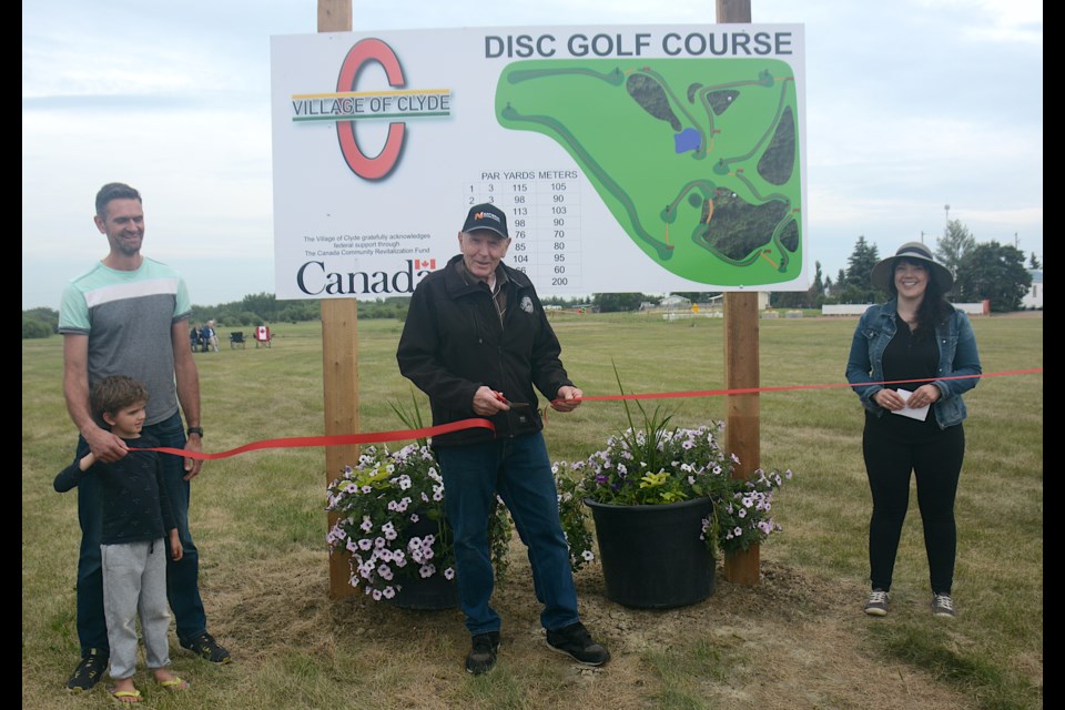 Former Village of Clyde Coun. Art Purdy, who came up with the suggestion for the disc golf course in Clyde got the honour of cutting the ribbon to officially open the course June 16. To the left is Coun. Philip Petkau and his youngest son Nathan, while mayor Charis Aguirre looks on. 