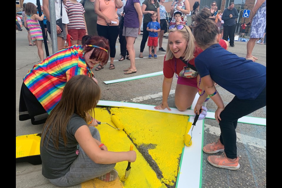 Starting at the left, then running counter clockwise: The first portion of the 106th Street Pride crosswalk in Westlock gets painted June 27 by graduating R.F. Staples School Grade 12 student Shaylin Lussier, a member of the school’s gay-straight alliance (GSA), the Thunder Alliance, Alarah Wells, 8, Linden Ducharme, 4, and Pembina Hills’ student-and-family advocate Heidi Mills, who’s also a member of the Thunder Alliance.