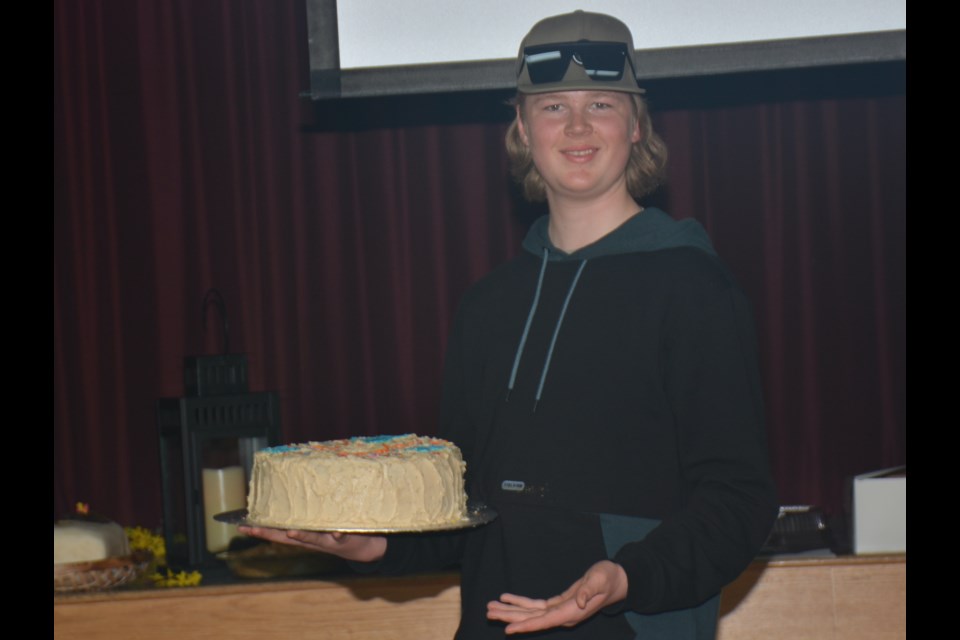 Ian van der Velde, a regular at Westlock’s Someplace Else, the home of YFC/Youth Unlimited, displays one of the cakes being sold at the organization’s annual fundraising event April 1 at Memorial Hall.