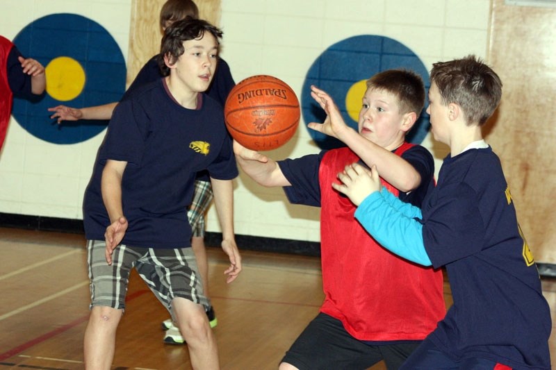 Rylan Durell of LTIS 2 passes the ball while Derek Greene (left) and Iver Steffes of LTIS 1 defend.