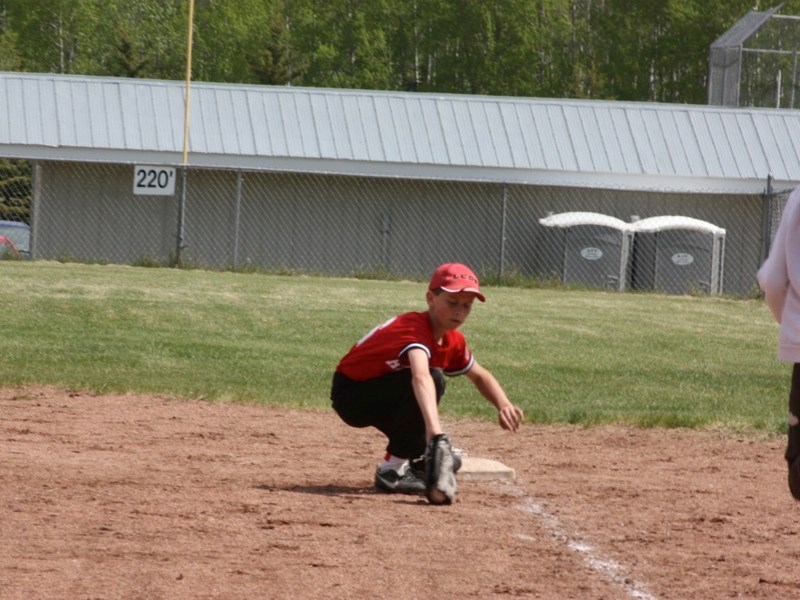 Jesse Weber of Athabasca&#8217;s Peewee Trappers scoops up the ball at first against Gibbons on Saturday.
