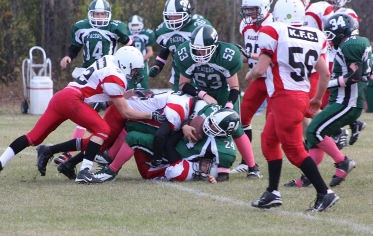 Ball carrier Mitchell Snow (24) of the Athabasca Pacers is swarmed by Vermillion players while teammates Andrew Morey (14), Brad Russell (36) and Brady Ballard (53) look on