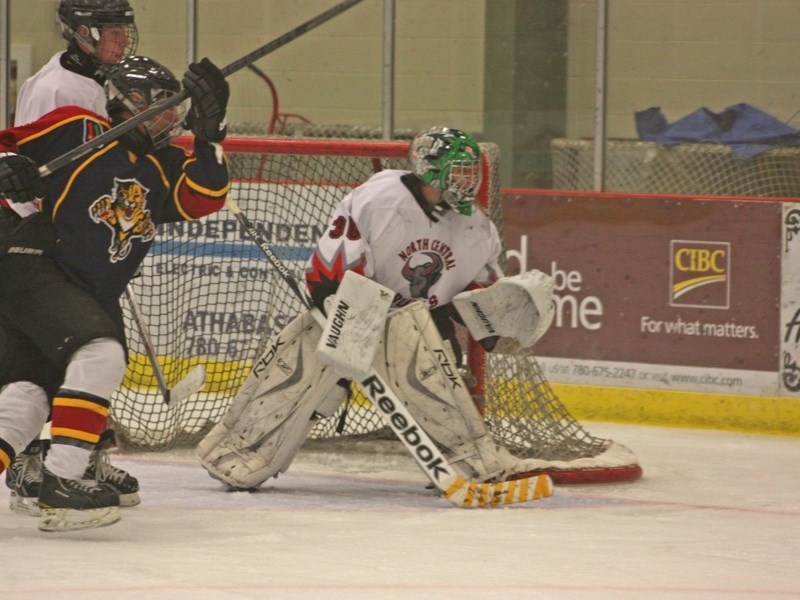 Goalie Mitchell Lovelace of the North Central Bulls midget &#8216;AA&#8217; hockey team keeps his eye out for the puck as a member of the Northeast Panthers battles Kody