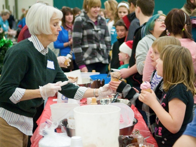 Volunteer Lois Schinkinger scoops ice cream during last year&#8217;s Community Christmas Dinner.