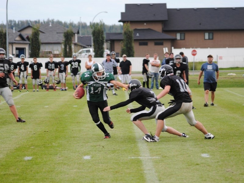 Athabasca&#8217;s Andrew Morey fends off an attack from two Hilltop High Whitecourt Cats players last Thursday during an exhibition game at Whitecourt&#8217;s Graham Acres