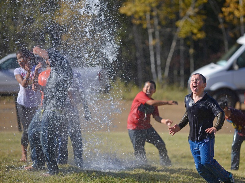 Gabriel Seguin (r) tries to take a drink from the fire hose spray that students played in last Friday at Landing Trail Intermediate School&#8217;s annual Flying High event.