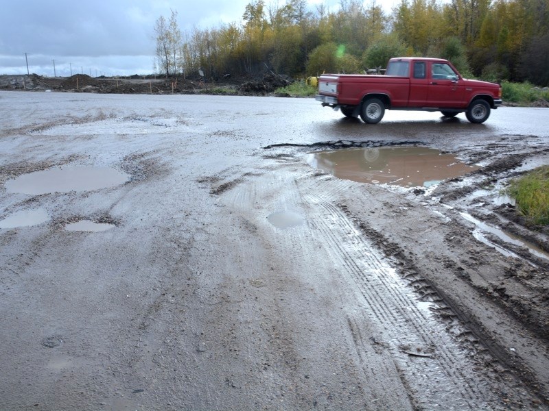A truck passes several potholes in Wandering River, which are causing concern for drivers and residents.