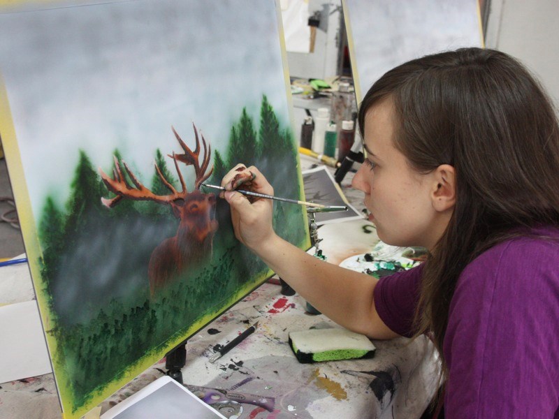 Mackenna Weber adds a few brushstrokes to her airbrushed painting of an elk last Sunday. Weber took part in a two-day airbrushing workshop at NTW Studio &#038; Gallery east