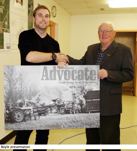 Athabasca town councillor Tanu Tyszka-Evans, left, presents Boyle Mayor Bob Clark with the village&#8217;s Centennial gift – a reprint of a photo taken back in 1954.