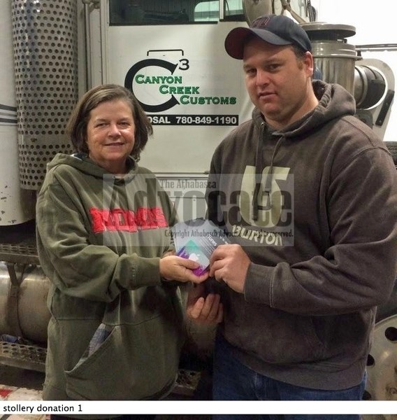Linda Saunders (l) accepts a donation from Jason de Champlain, owner of Canyon Creek Customs in Slave Lake, who was one of the first companies to donate to the cause.