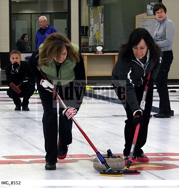 Sherry Tebbenham and Kelly Cooper sweep the rock tossed by Stan Lyle, which helped their rink on the road to the A-event title.
