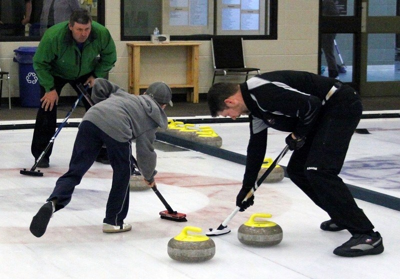 Kevin Senyk urges Josh and Kurtis Wiselka to go hard on the brooms to get there stone to the four foot during the second end of the A final of the Athabasca Men&#8217;s