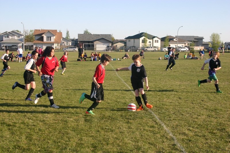 (r-l) Ethan Deveau of the Athabasca U12 Lightning Bolts is challenged by Jacob Hayward of the Barcelona Juniors, followed closely by Jodacee Cardinal and Gavin Neaves. This