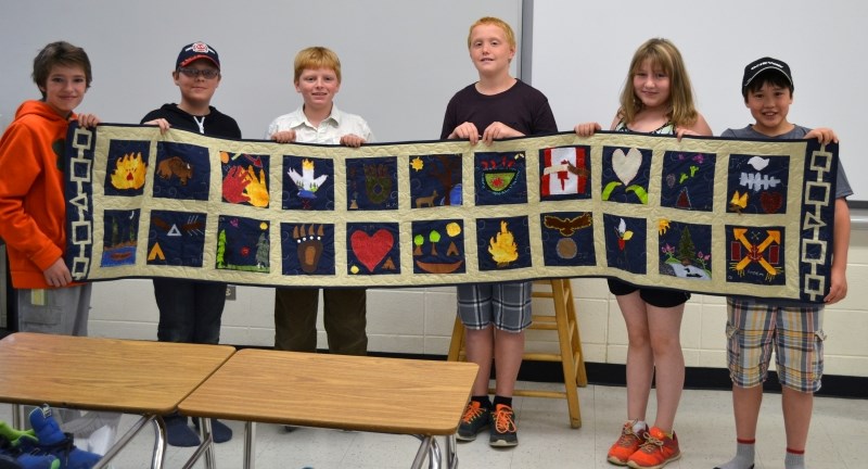 LTIS Grade 6 students hold up the quilt they made as part of last year&#8217;s arts integration pilot.