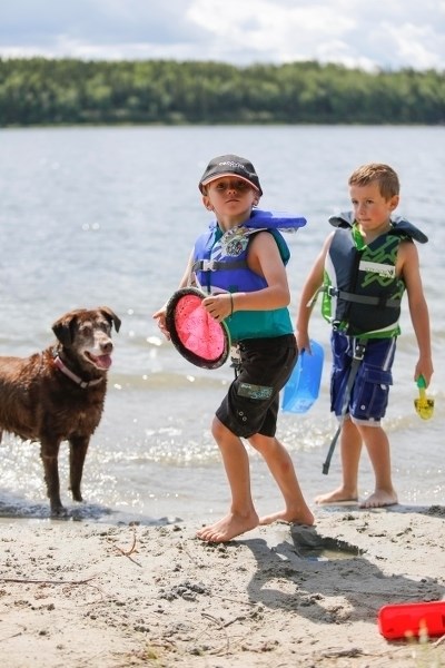 Six year old Elijah Roussel (left) and Connor Farkasdi play fetch with their Chocolate Lab named Dutch at Skeleton Lake during the August long weekend.