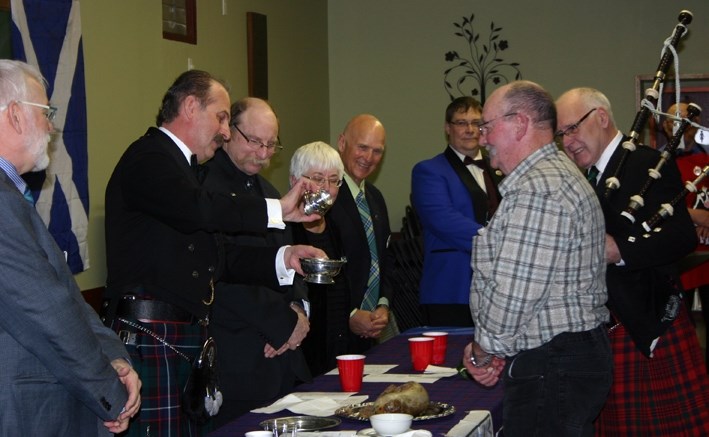 Blair Mitchell pours a &#8220;wee dram &#8221; for haggis bearer Henry Baker and piper Angus Campbell as part of &#8220;piping in the haggis &#8221; Friday at the Legion.