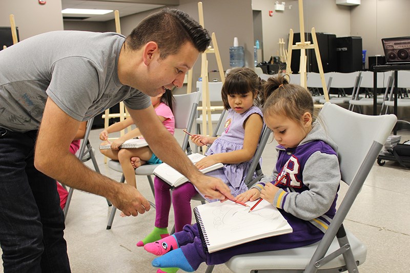 Lance Cardinal teaches a Calling Lake student how to draw during one of the Arts Academy&#8217;s classes.