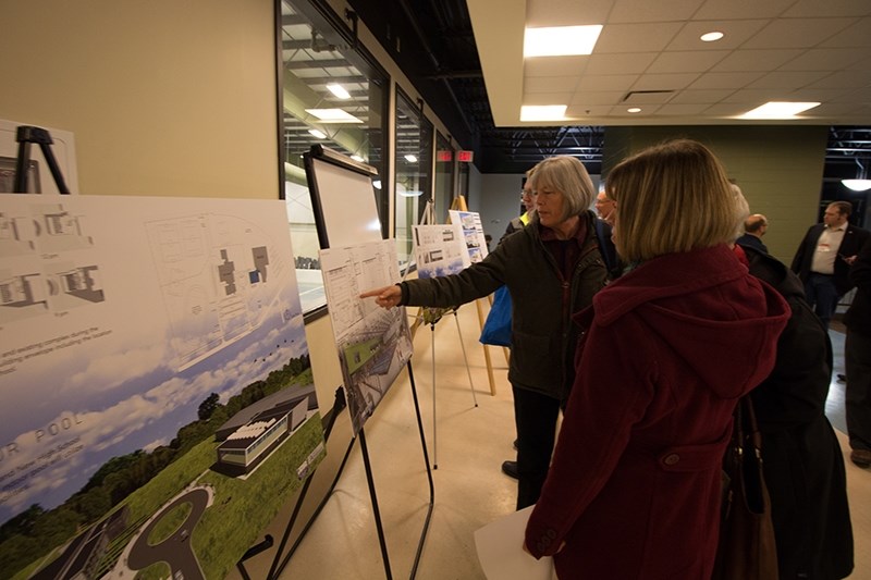 Florene Ypna (right) looks on as Liza Russell points to a board at the pool committee&#8217;s open house on Dec. 1.