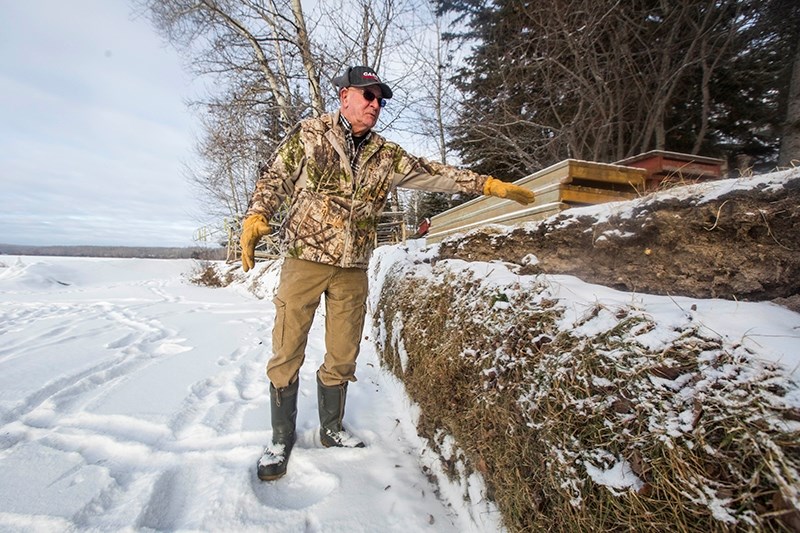 Bob Lindsay stands next to a pile of dirt pushed back from the ice pressure along the southwest shoreline.