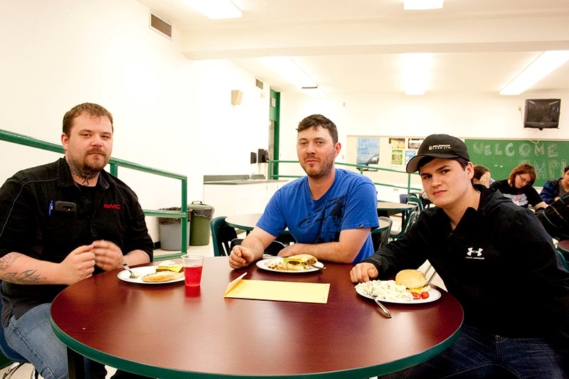 Andrew Toyne and Justin Nicholson have a burger with their work experience student, Braiden Casselman. (Below) Blaine Trindle holds up his Most Improved Student award.
