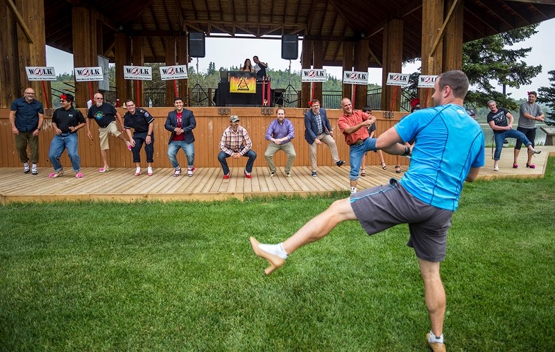 Jon LeMessurier warms up the men participating in the seventh annual Walk a Mile in Her Shoes event Sept. 8, before they take to the streets to promote awareness of