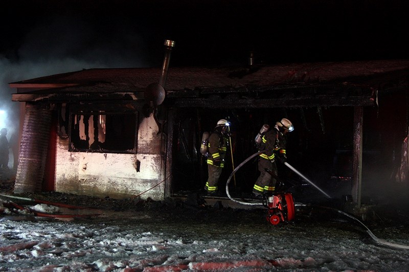 Firefighters spray water inside the smoking home on Highway 663 west of Colinton Jan. 24. RCMP and EMS also responded to the scene.