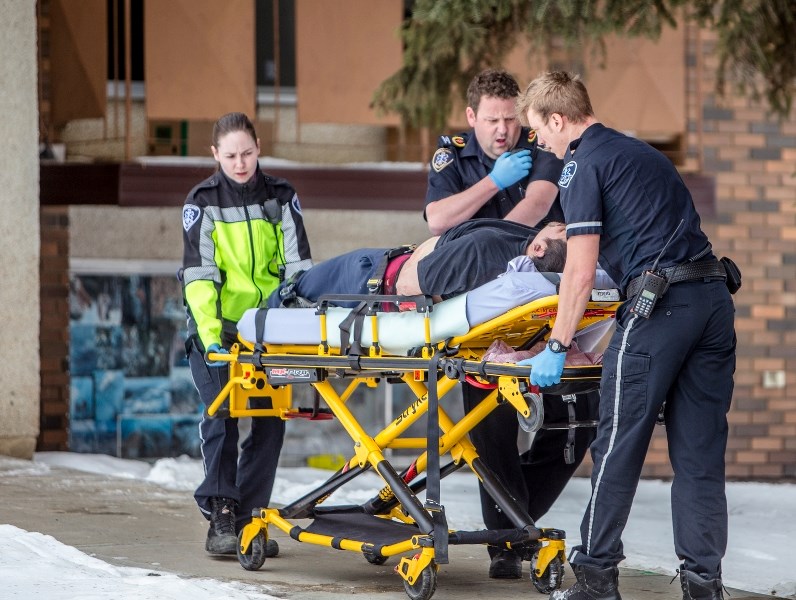 A man with severe bleeding is led out of Spruceland Apartments in Athabasca by Emergency Medical Services shortly before 11 a.m. March 2.
