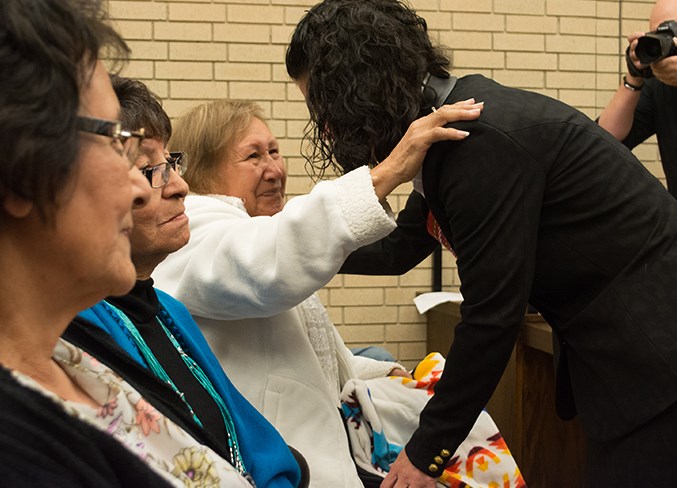  Christensen-Moore (right) hands a blanket to Vivian House from Calling Lake.