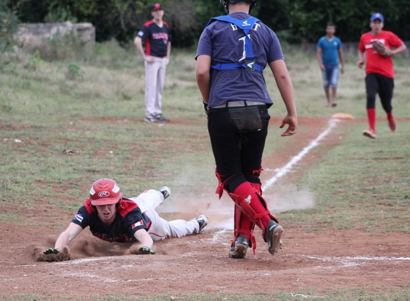 Branden Meier makes a head first slide to touch home plate.