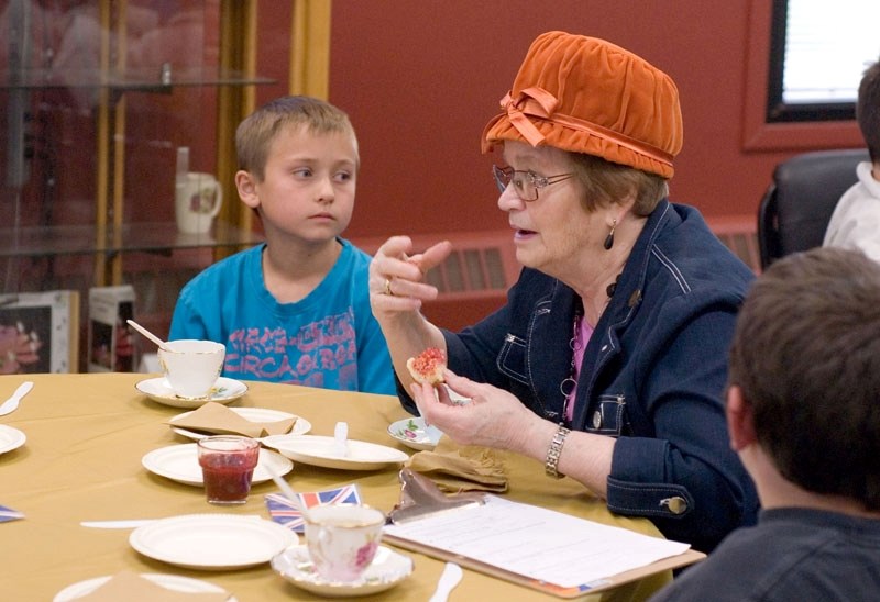Crumpet in hand, Hillcrest Lodge resident Bessie Kuhn tells a story as Brendan Bojold listens intently. Students were equipped with a clipboard of questions to ask their