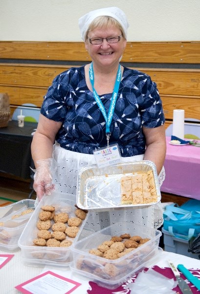 Smiling ear to ear, Darlene Slepanki of Feasts Made Easy Catering displays treats available at her Germany booth.