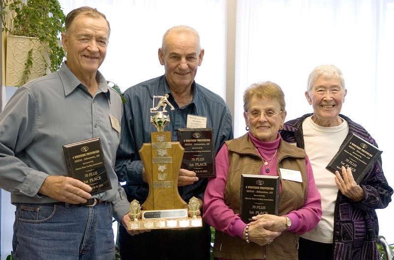 Bert Dube, Stan Schultz, Mary Dube, and Faye Schultz stand with their trophy and plaques from the 4 Western Provinces curling tournament.